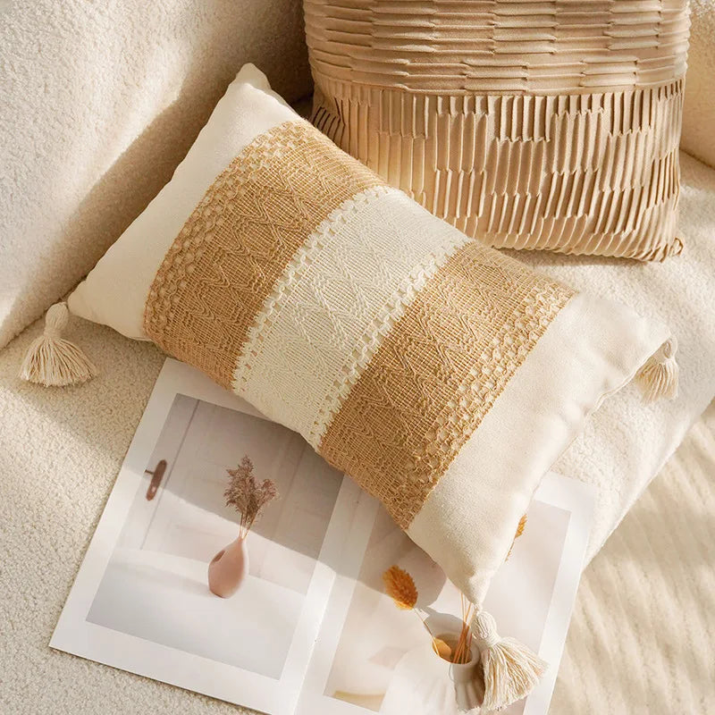 Textured pillow with tassels on a soft surface next to a woven basket.