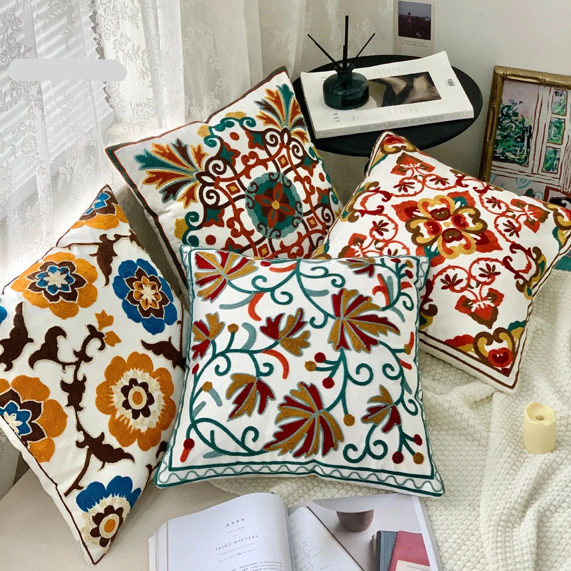 Decorative pillows with floral patterns on a white surface, featuring the brand My Boho Home. Handcrafted embroidered cushion cover on armchair – modern boho living room decor