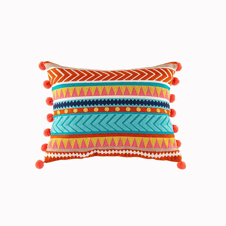 Colorful patterned pillow with pom-pom details on a white background. Bohemian embroidered throw pillow cover with geometric design, cotton-blend cushion for sofa, bed, or modern home decor.