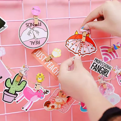 Hand arranging various decorative stickers on a pink grid background