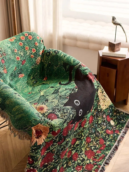Decorative green blanket with floral patterns draped over a chair in a room. Cat woven throw blanket for boho sofa and home decor
