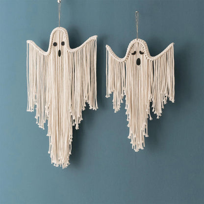 Two cream macrame ghost wall hangings with long fringe and small black embroidered faces, hanging against a muted blue-gray wall from My Boho Home