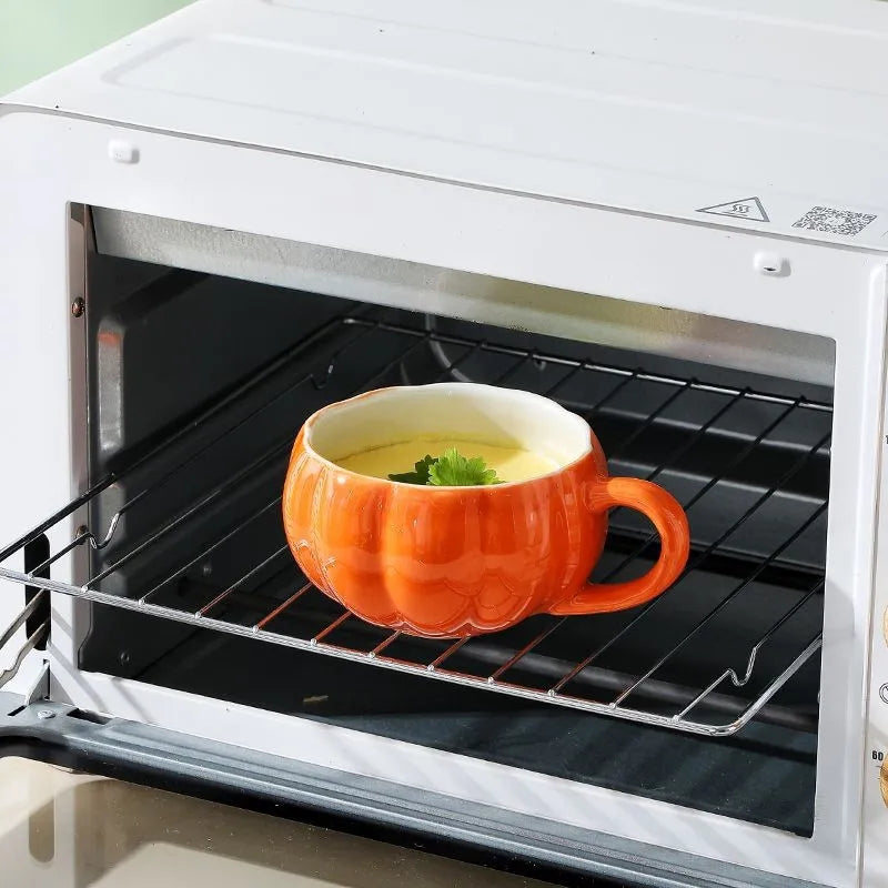 Orange pumpkin-shaped mug with a white interior on an open oven rack. Pumpkin ceramic mug with spoon Halloween autumn fall coffee cup