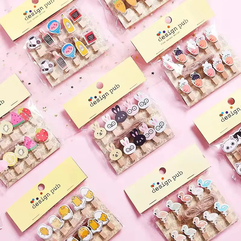 Collection of wooden clip sets with 'design pub' packaging on a pink background