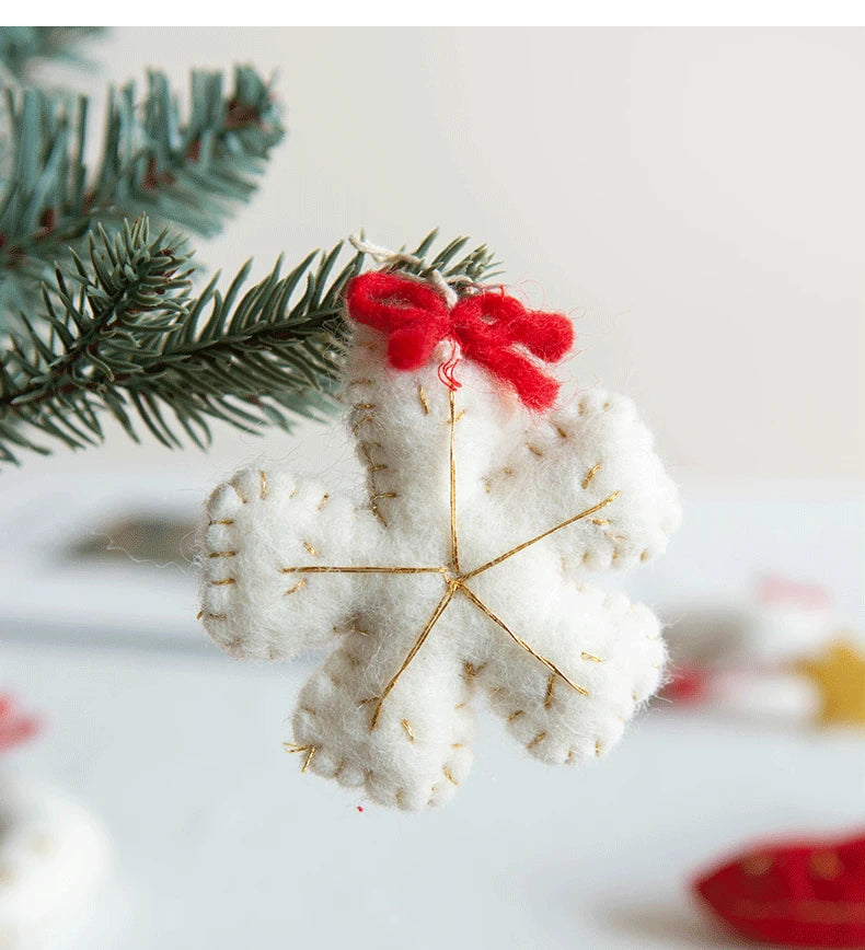 White snowflake ornament with gold accents and a red bow on a blurred Christmas tree background.