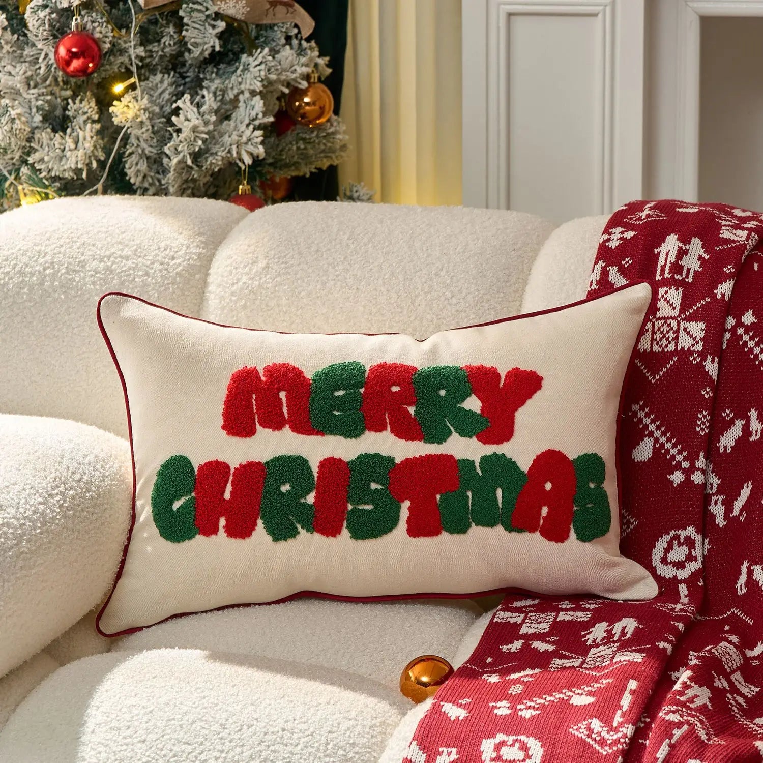 Decorative pillow with 'Merry Christmas' text on a couch with a Christmas tree in the background