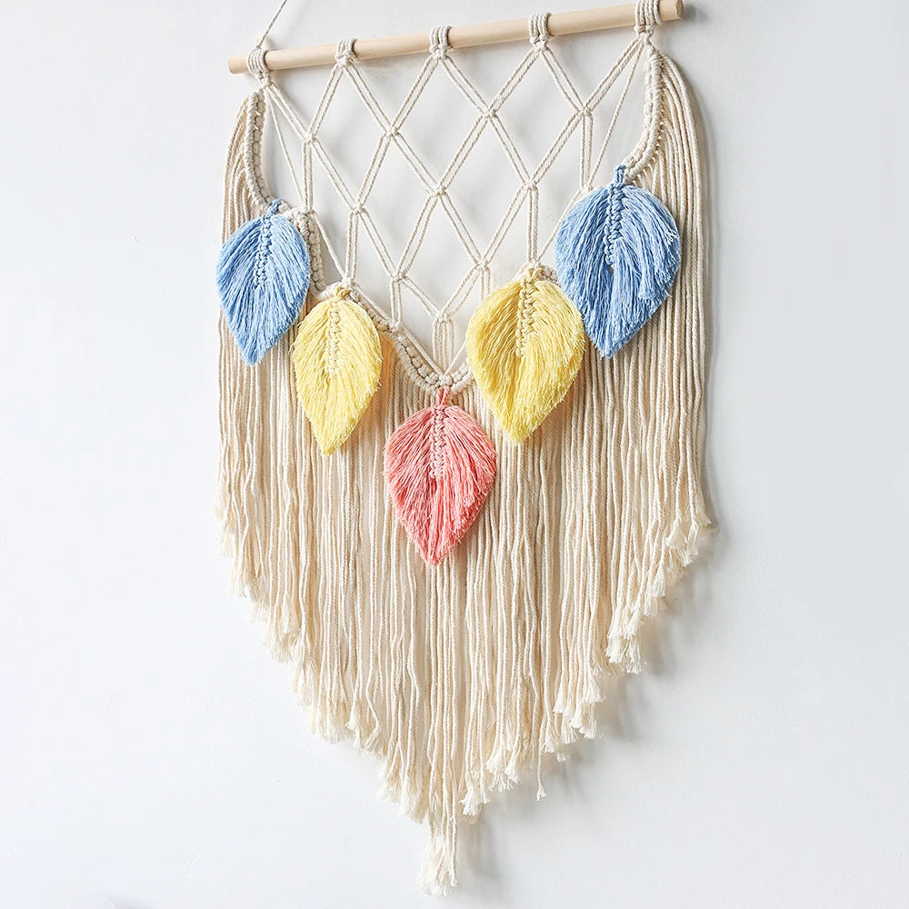 Macrame wall hanging with colorful leaf-shaped decorations on a white background