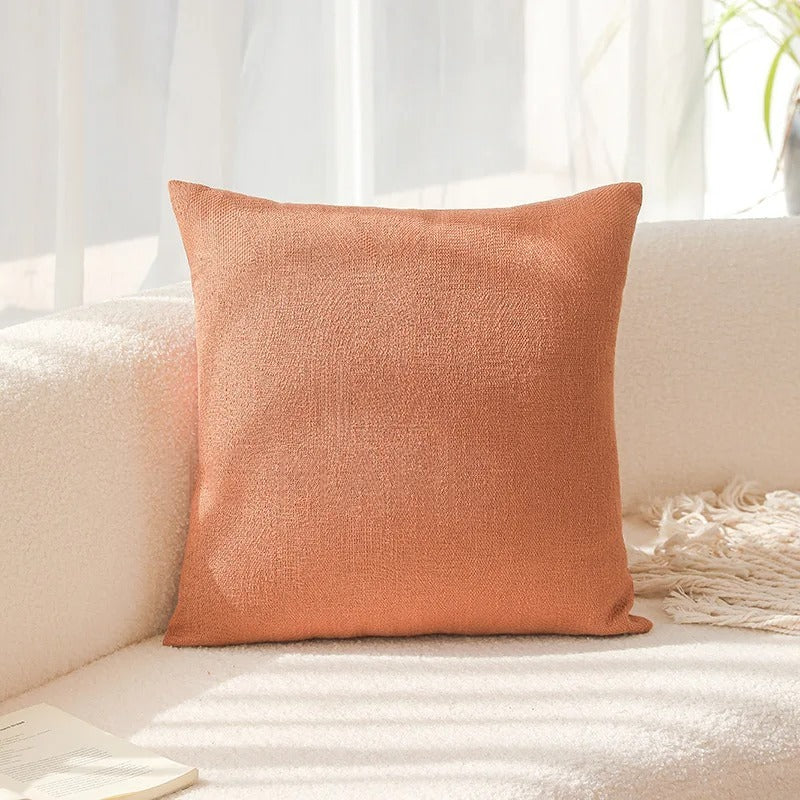 Orange textured pillow on a white couch with a light background