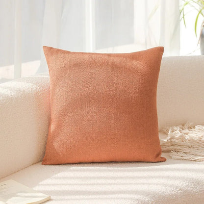 Orange textured pillow on a white couch with a light background