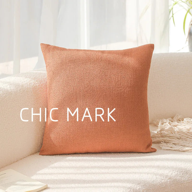 Orange pillow with 'CHIC MARK' text on a white couch. Modern yarn-dyed throw pillow cover, luxury textured decorative cushion for sofa, bed, or window seating in soft neutral tones.