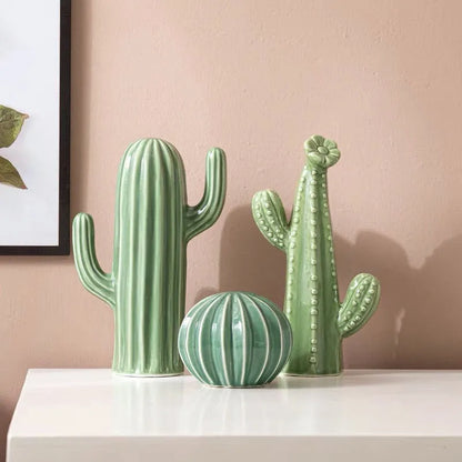 Three green cactus-shaped vases on a white surface with a pink wall background. Nordic ceramic cactus ornament for modern home decor