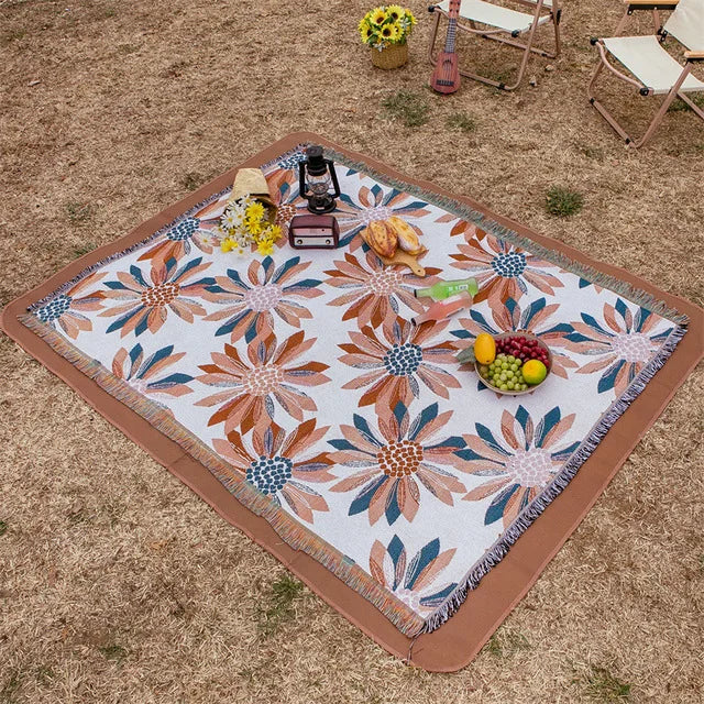 Floral patterned picnic blanket on a sandy ground with picnic items. Mediterranean style woven cotton throw blanket boho home decor