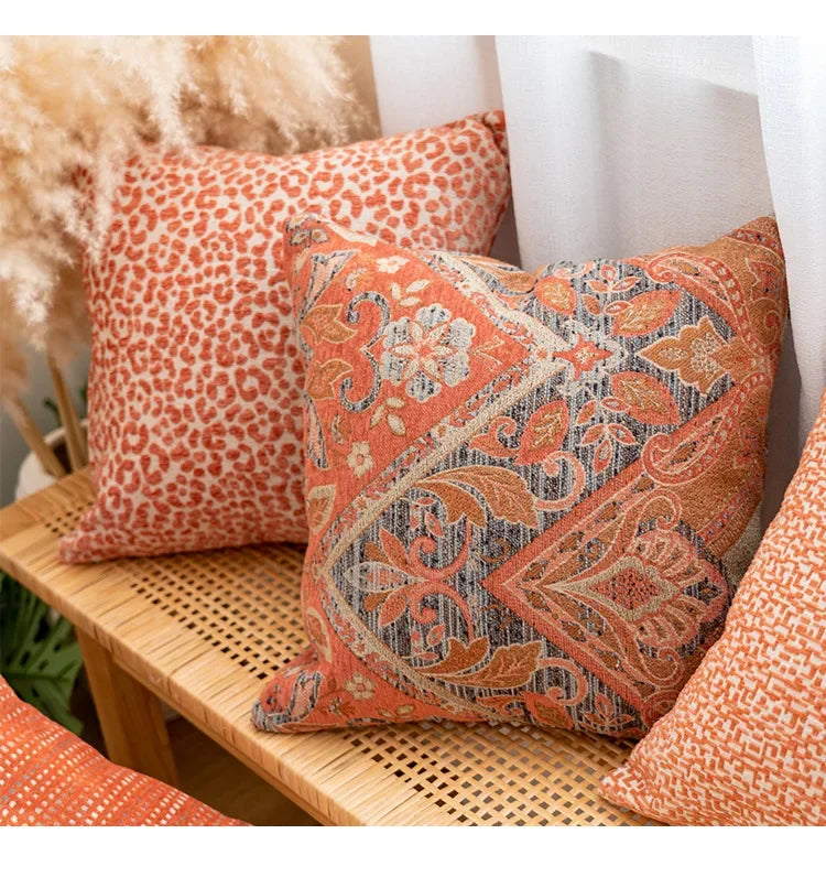 Decorative pillows with orange and brown patterns on a wicker chair.