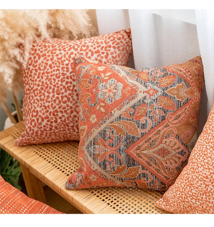 Decorative pillows with orange and brown patterns on a wicker chair.