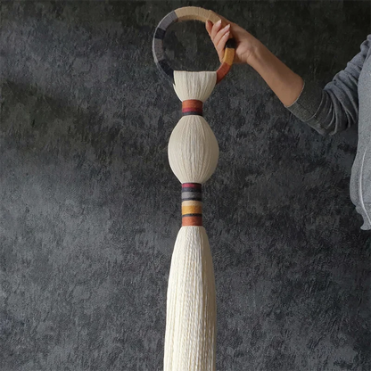 Decorative tassel held by a hand against a dark background. boho macrame wall art