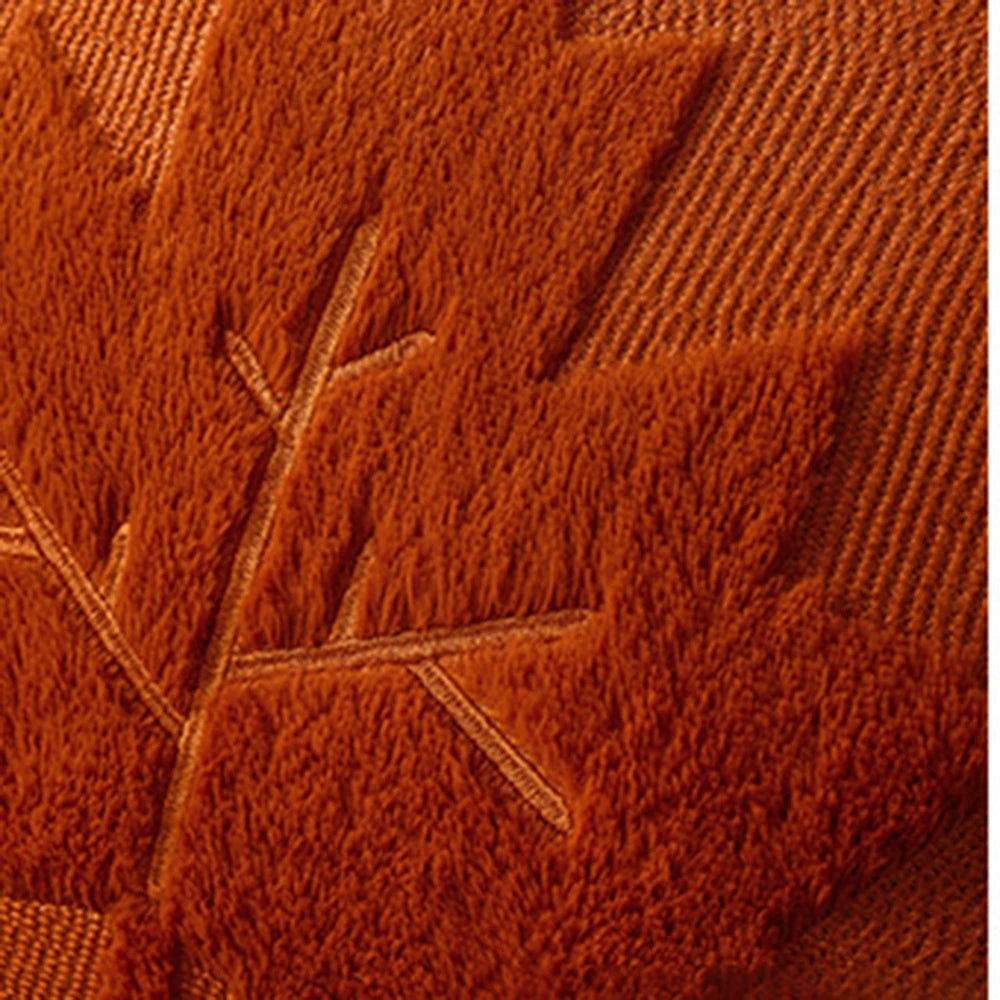 Close-up of textured brown fabric with leaf pattern. Halloween pumpkin plush pillow cover for sofa and bed decor