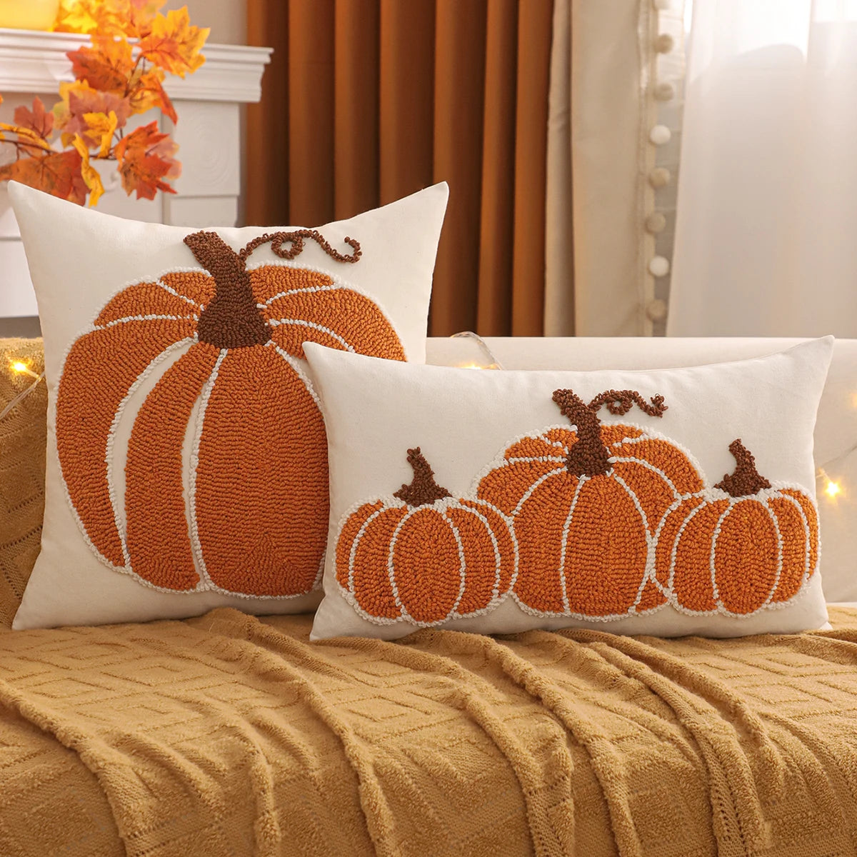 Two pumpkin-themed decorative pillows on a couch with autumn decorations in the background. Festive fall pillow cover for Halloween and Thanksgiving décor
