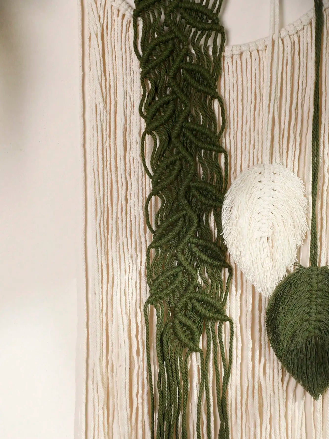 Close-up of green knitted or crocheted fabric with a textured pattern on a neutral background.