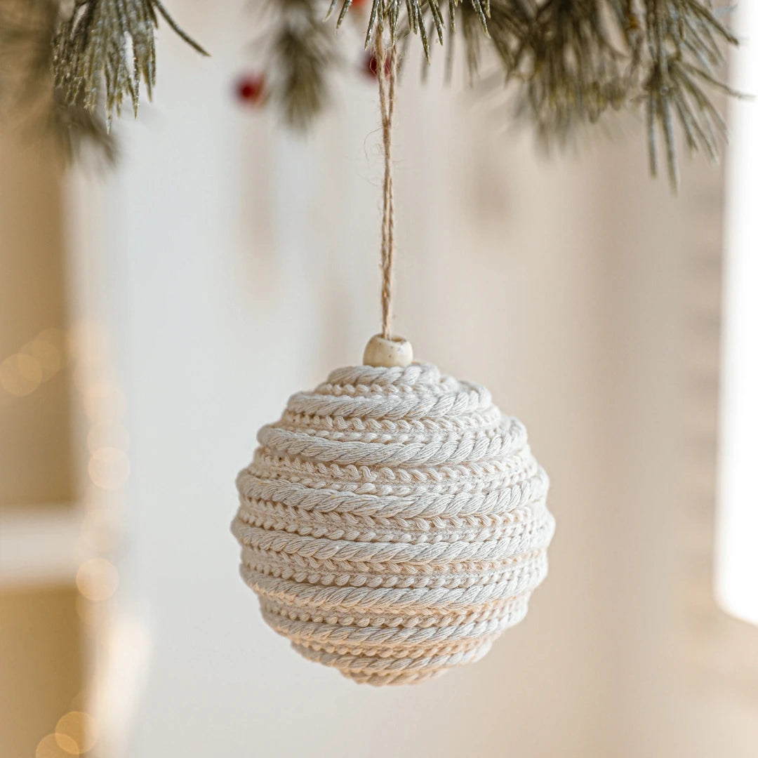 Textured spherical ornament hanging on a tree branch with a blurred background