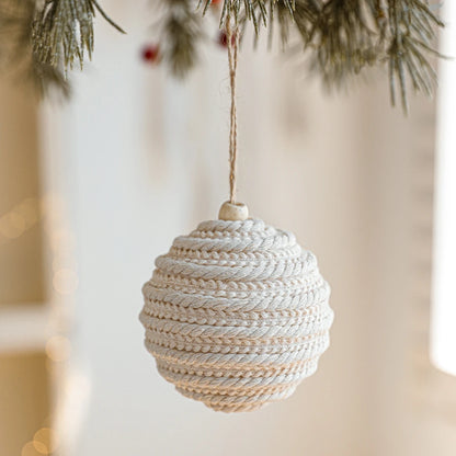 Textured spherical ornament hanging on a tree branch with a blurred background
