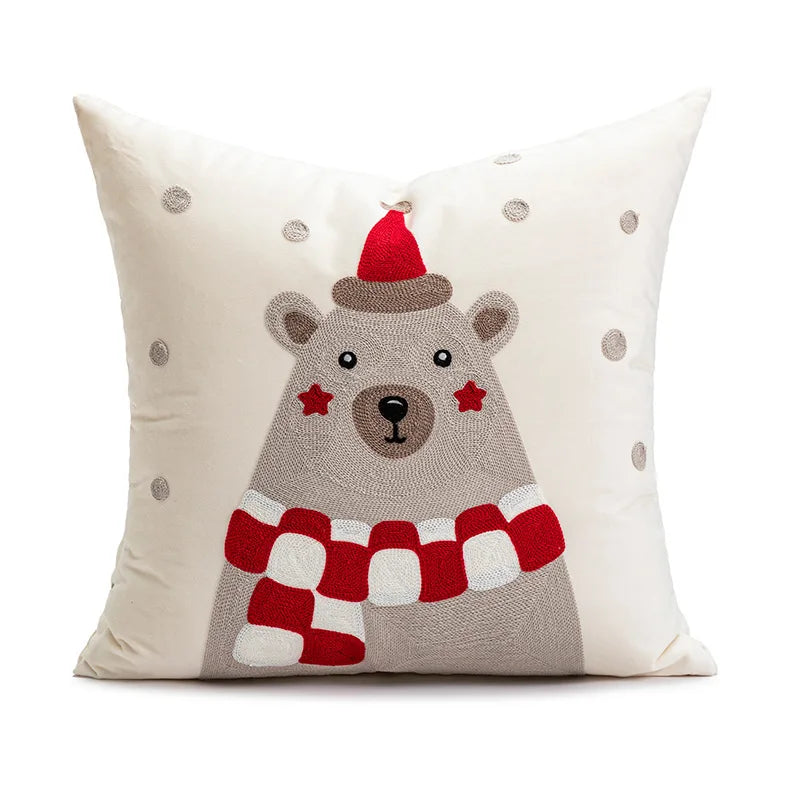 Decorative pillow with a bear design wearing a red hat and scarf on a white background