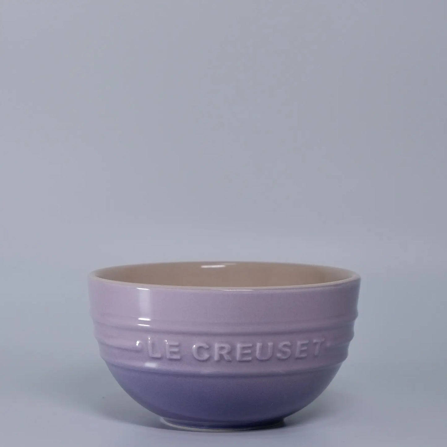 Purple ceramic bowl with 'LE CREUSET' branding on a gray background Gradient ceramic rice bowl in bright colors, bone china soup and noodle bowl, dessert and pudding kitchen tableware for boho home dining