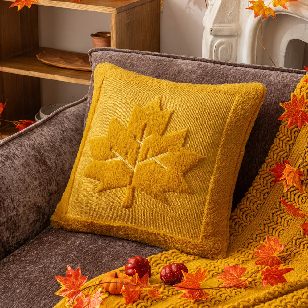 Yellow pillow with leaf design on a brown sofa, surrounded by autumn decorations. Halloween pumpkin plush pillow cover for sofa and bed decor.