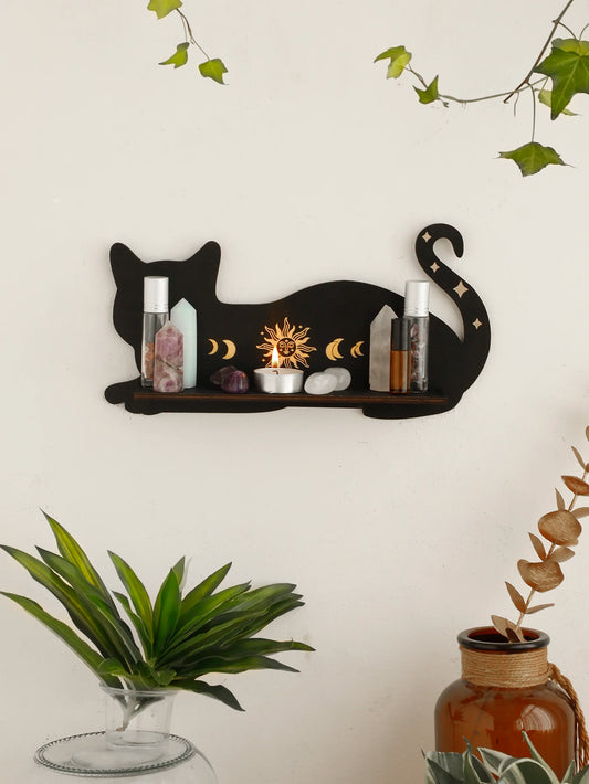 Decorative wall shelf shaped like a cat with various items on a light-colored wall.