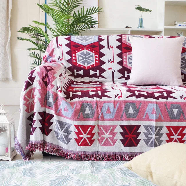 Patterned blanket draped over a sofa with a white pillow in a living room setting. Mediterranean style woven cotton throw blanket boho home decor