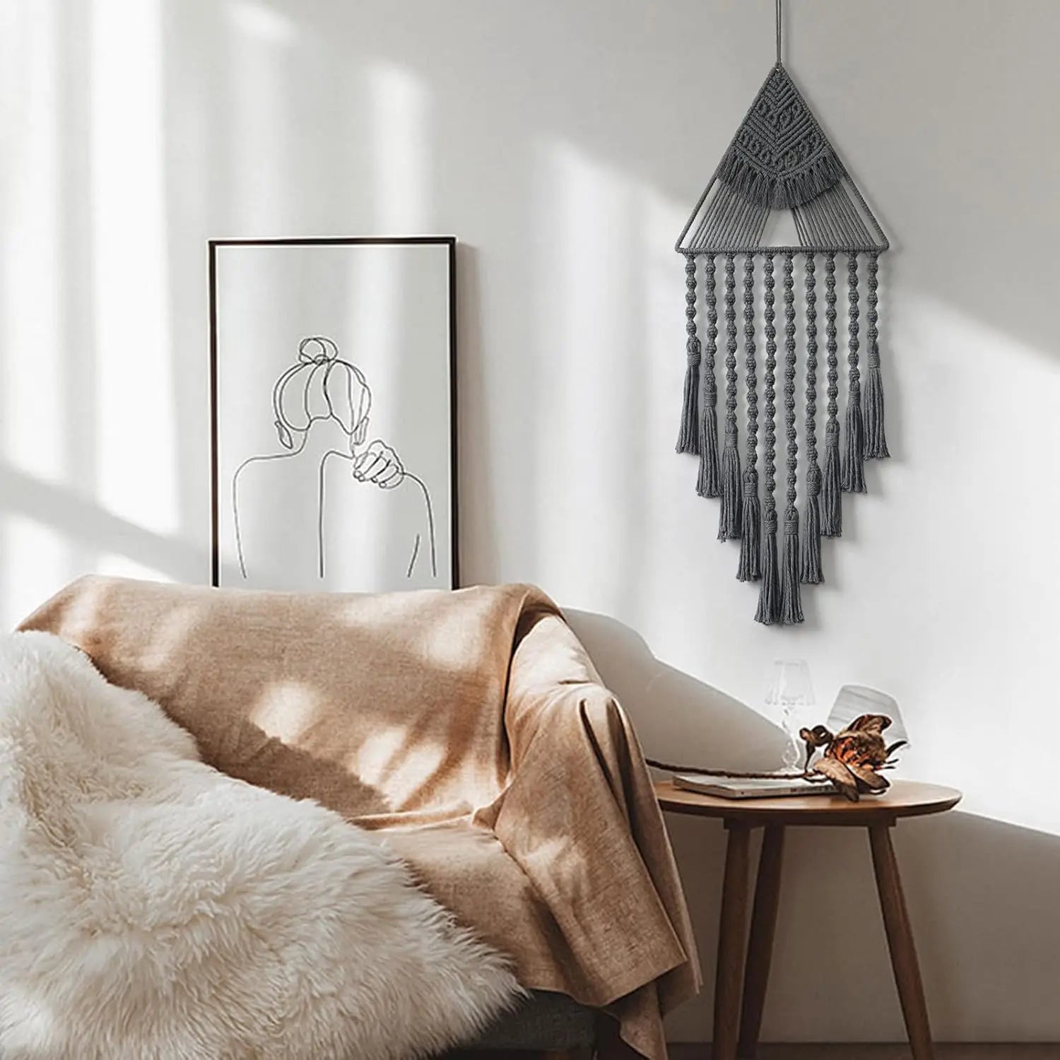 Cozy living room with a beige blanket draped over a chair, a framed artwork on the wall, and a macrame wall hanging. boho home decor, macrame wall hanging, triangle dream catcher, woven tapestry, handmade cotton wall decor, tassel wall hanging, bedroom door decor, housewarming gift, rustic bohemian art, boho apartment wall decor, neutral textile art