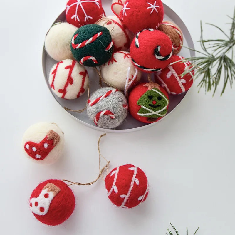 Felt Christmas ornaments in various designs on a white surface with a small bowl.