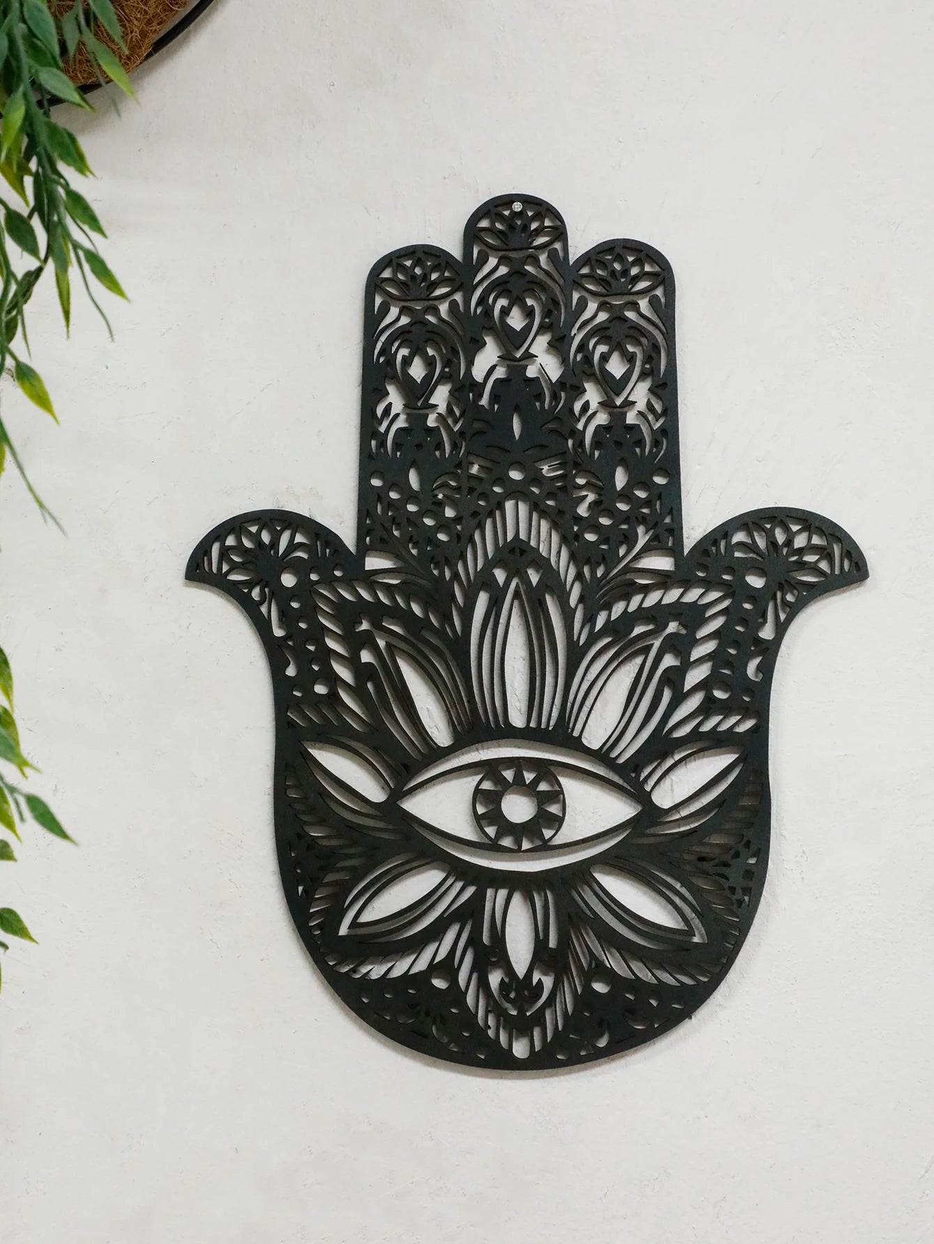 Black hand-shaped wood wall decor with protective evil eye, photographed against neutral background for alternative room styling.