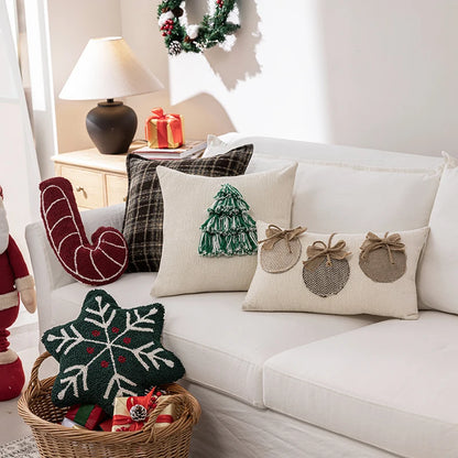 Decorative pillows on a white couch with a Christmas theme, including a tree, star, and gift box designs.