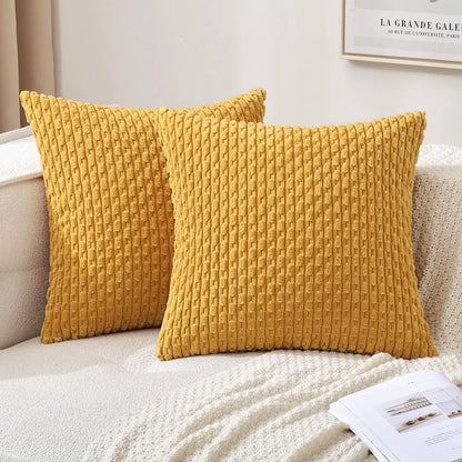 Two textured yellow pillows on a beige sofa with a white blanket and magazine.