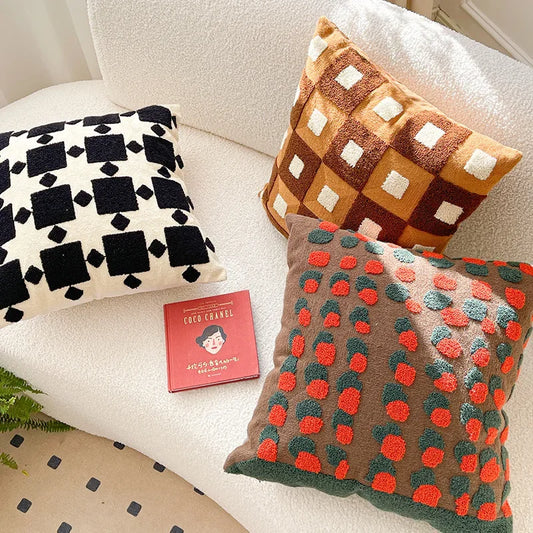 Three patterned cushions on a sofa with a small book titled 'Coco Chanel' in the center. Bohemian embroidered throw pillow cover 18x18 inch with geometric towel embroidery, decorative cushion for sofa, bed, or living room boho home decor