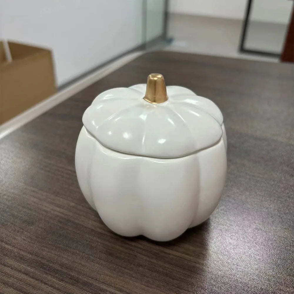 White ceramic pumpkin-shaped container with a gold lid on a wooden surface. fall home decor