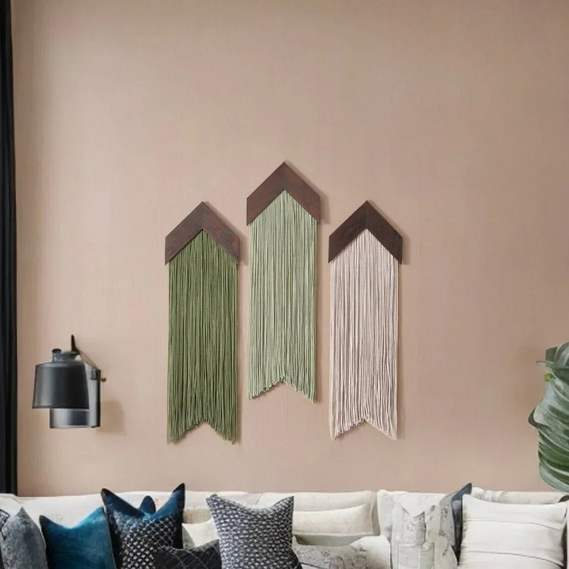 Three wall art pieces hanging on a beige wall above a white sofa with decorative pillows.