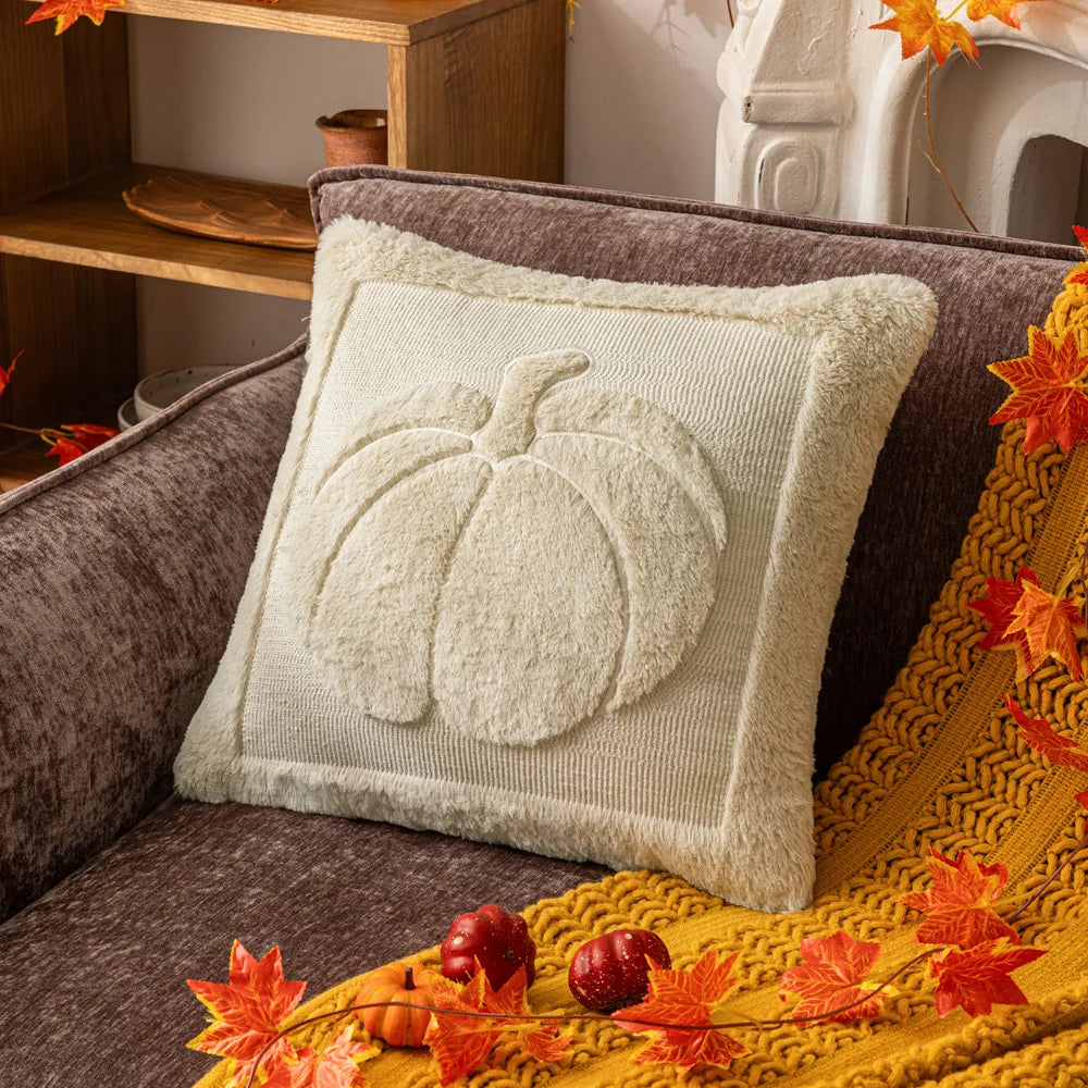 Decorative pillow with pumpkin design on a brown couch with autumn leaves. Halloween pumpkin plush pillow cover for sofa and bed decor.