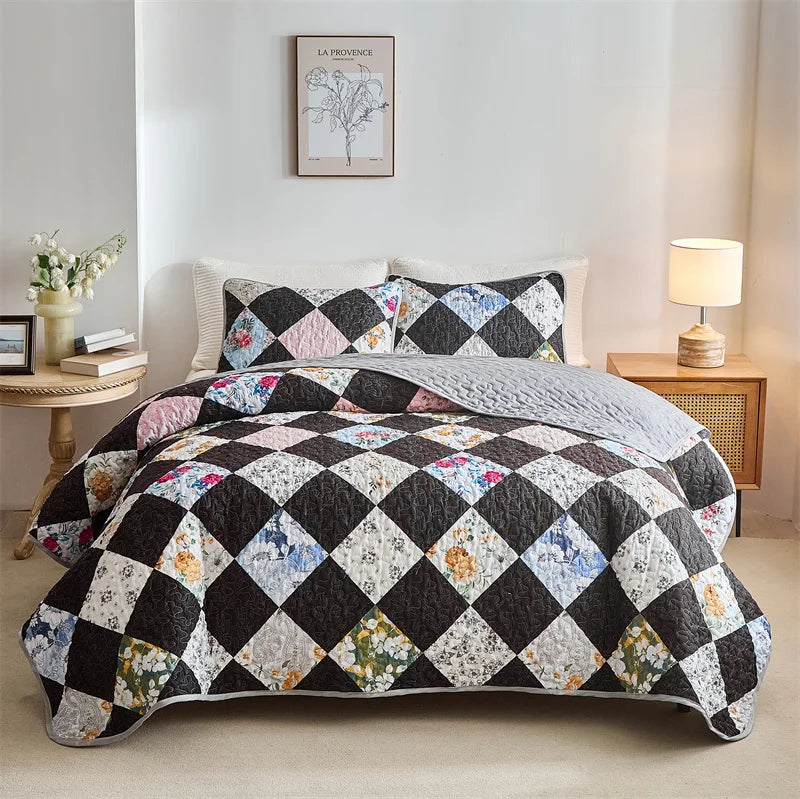 Floral patchwork quilt on a bed in a bedroom setting with a lamp and decor. Lightweight boho quilted bedspread set with pillow shams, soft all-season coverlet for queen, king, full, or twin beds in modern cloud pattern design.