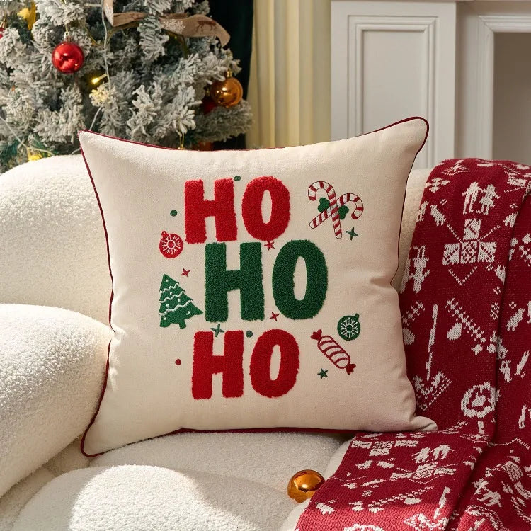 Decorative pillow with 'HO HO HO' text on a couch next to a Christmas tree.