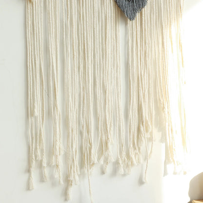 Textured wall hanging with yarn strands on a white wall
