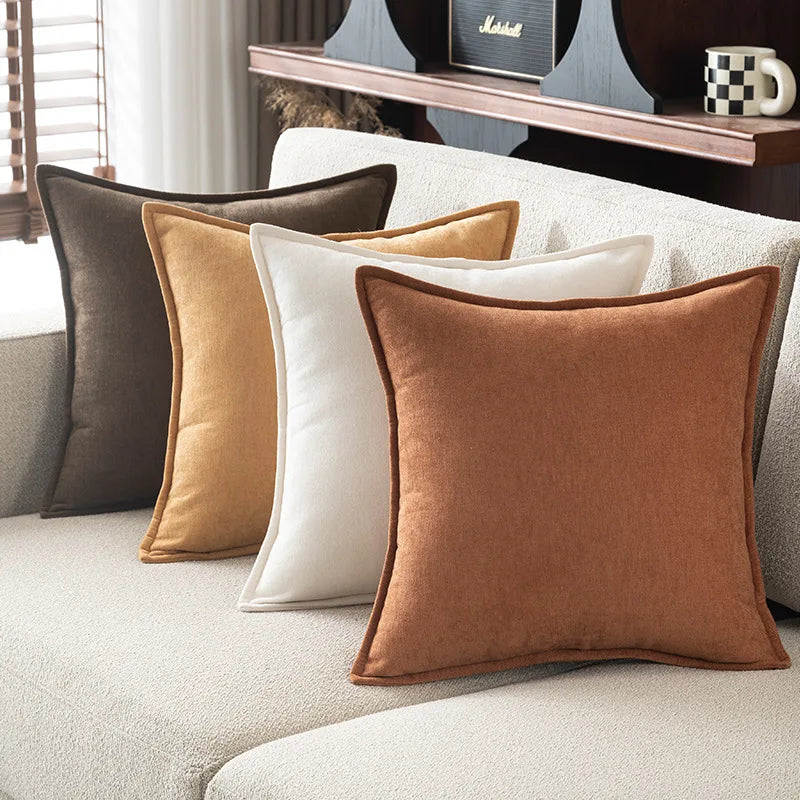 Set of four pillows in brown, beige, and white on a sofa.