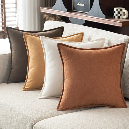 Set of four pillows in brown, beige, and white on a sofa.