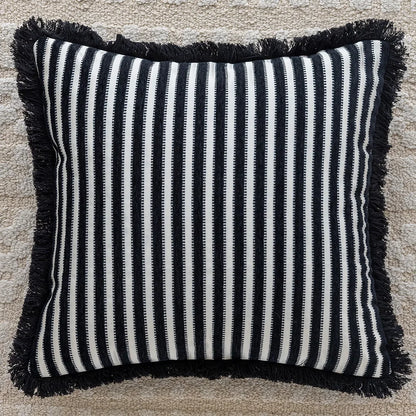 Striped pillow with black and white pattern and frayed edges on a textured surface. embroidery throw pillow cover in boho modern style
