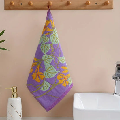 Purple tea towel with floral pattern hanging on a wooden towel rack above a sink.