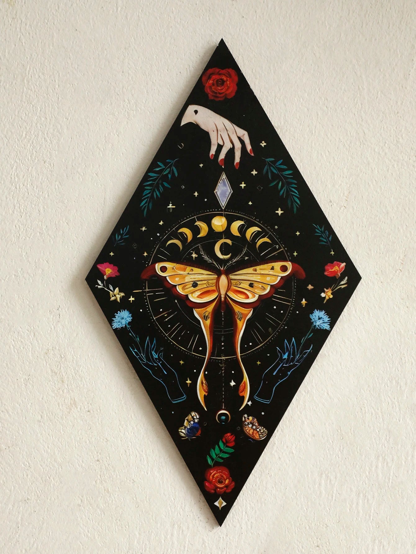 Decorative panel with a butterfly, moon phases, and hand design on a black background. Rustic colorful wood wall art panel with moon, stars, and butterfly engraving, displayed above a sofa in a boho-styled living room