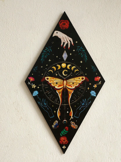 Decorative panel with a butterfly, moon phases, and hand design on a black background. Rustic colorful wood wall art panel with moon, stars, and butterfly engraving, displayed above a sofa in a boho-styled living room