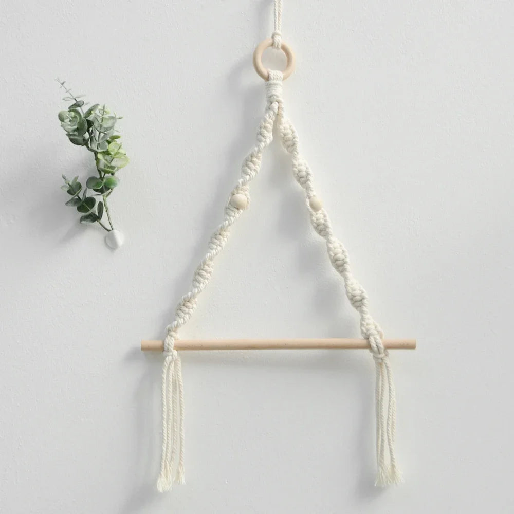 Macrame plant hanger with wooden rod and decorative elements on a light gray background boho home decor, toilet paper holder, bohemian bathroom accessory, tissue holder, wall-mounted towel rack, cotton rope toilet paper rack, wooden bead towel holder, rustic home decor, boho wall decor, bathroom organization, housewarming gift