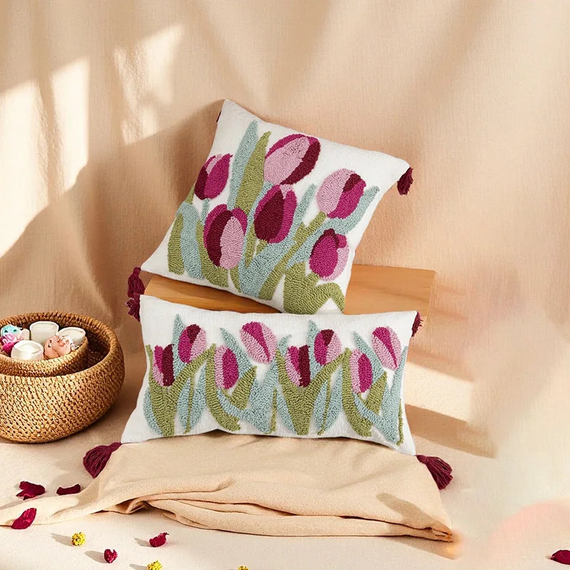 Floral patterned pillows on a beige surface with a woven basket and decorative items.