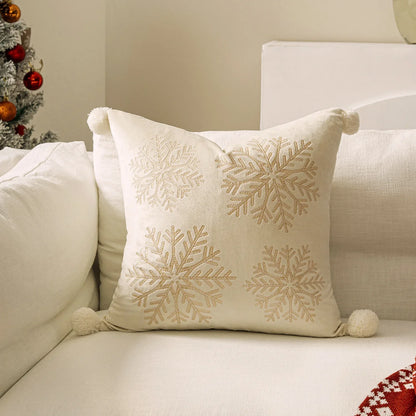 Decorative pillow with snowflake patterns on a beige couch next to a Christmas tree. Embroidered Merry Christmas pillow cover with snowflake design – festive red and white holiday cushion for sofa or bedroom décor.